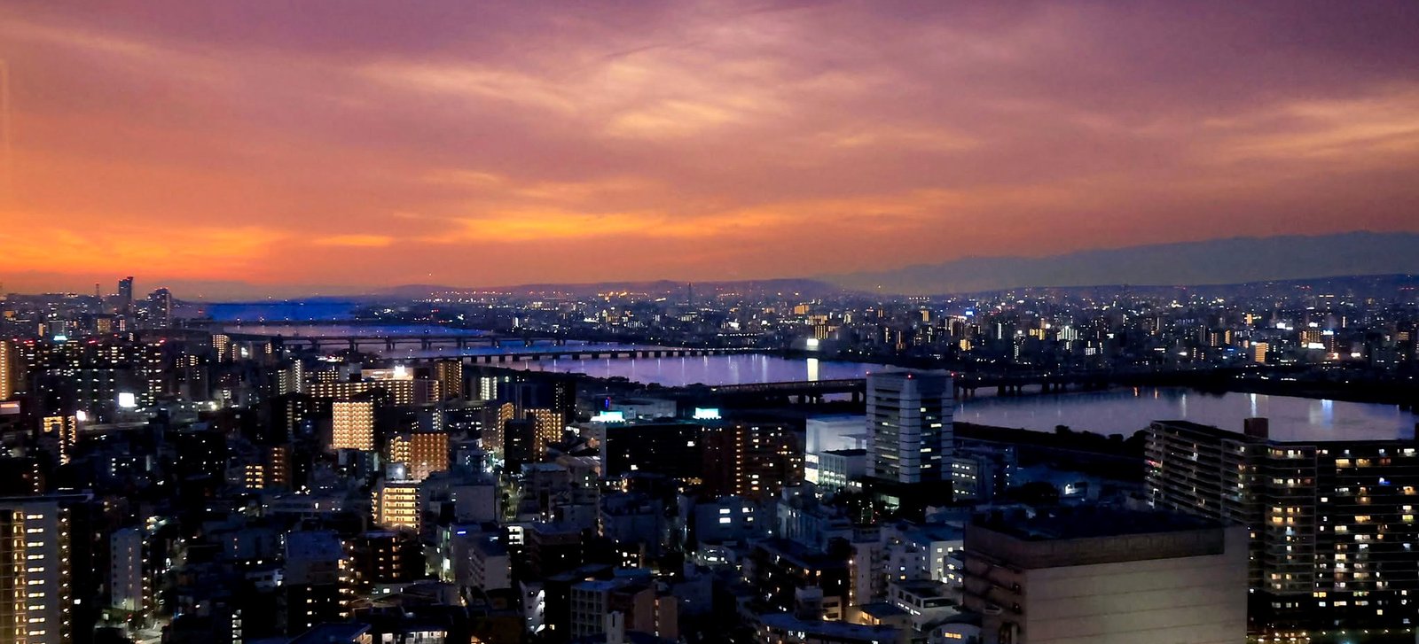 Vista panorâmica de Osaka ao pôr do sol, com o rio Yodo e a cidade iluminada