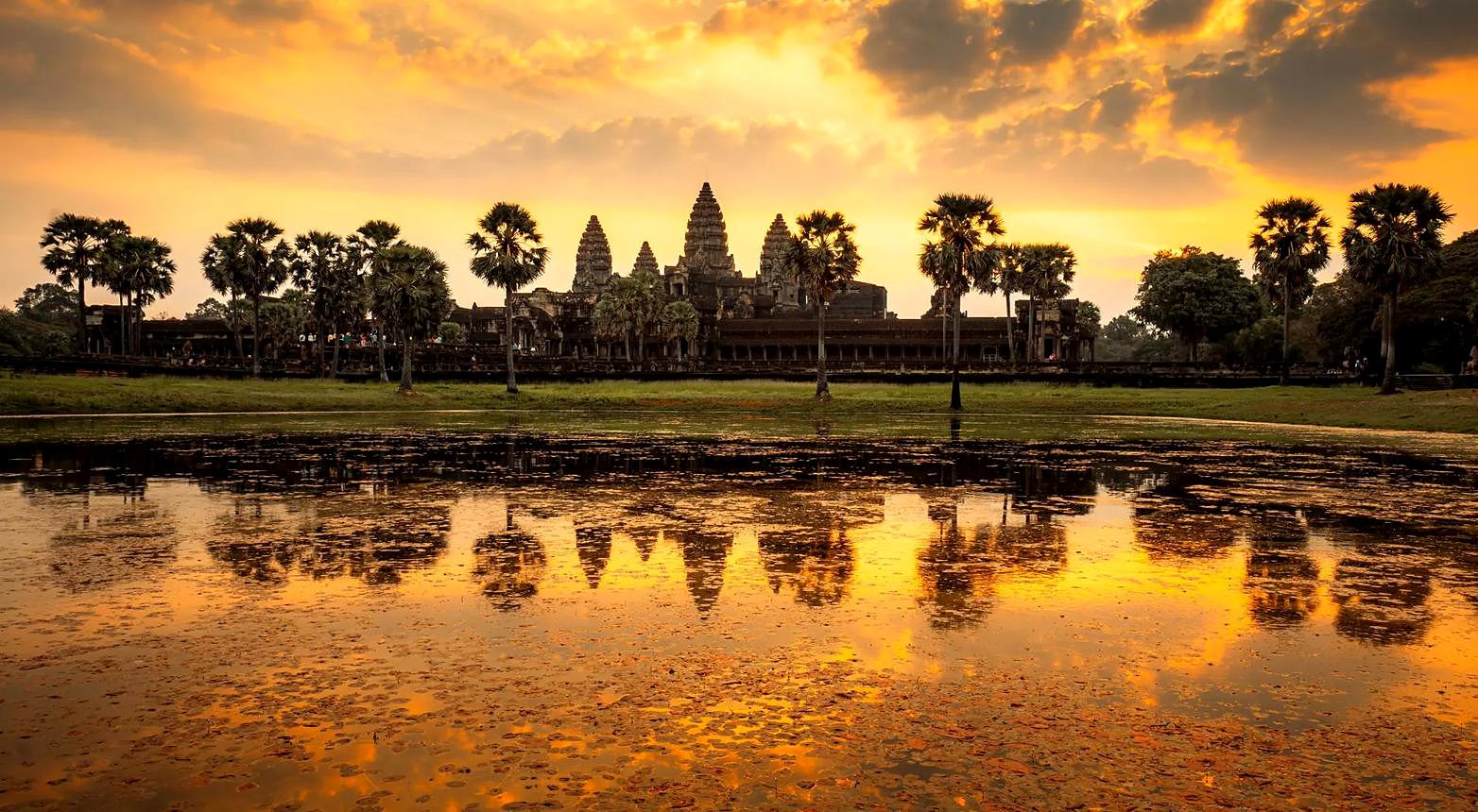 Silhueta das torres de Angkor Wat ao nascer do sol refletida no lago, em Siem Reap, Camboja
