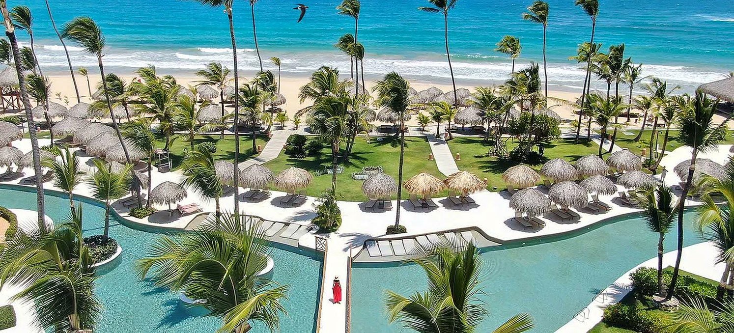 Resort pé na areia em Punta Cana com piscinas, coqueiros e mar azul do Caribe