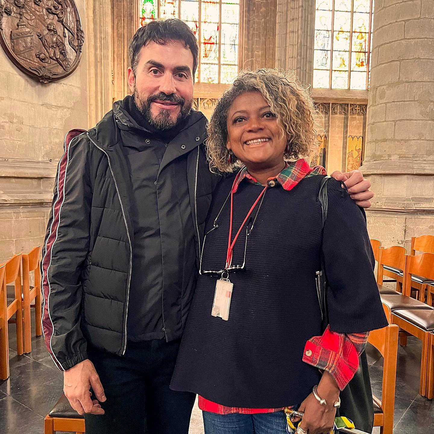 Graça sorrindo ao lado de um viajante brasileiro no interior de uma igreja