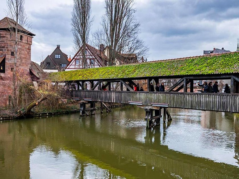 Pedestres atravessando a ponte de madeira Henkersteg, a Ponte do Carrasco, sobre o rio Pegnitz em Nuremberg