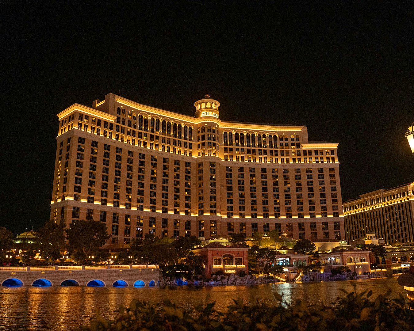 Fachada do hotel Bellagio iluminada à noite em frente ao lago das fontes