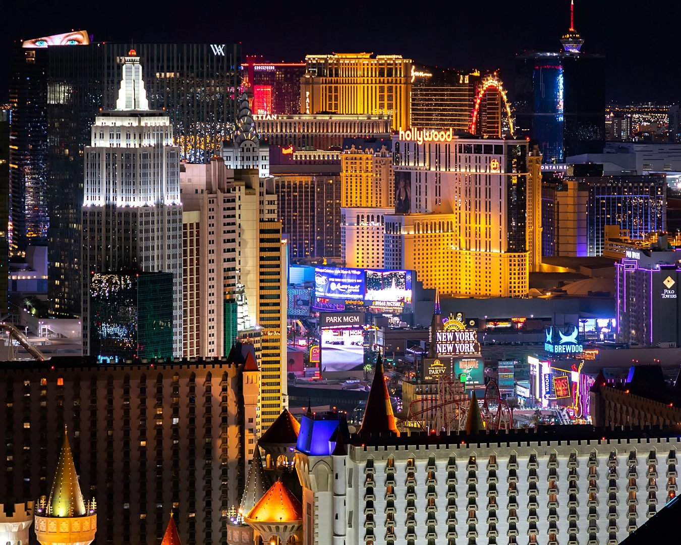 Vista noturna da Las Vegas Strip com os hotéis New York New York, Excalibur e Park MGM iluminados