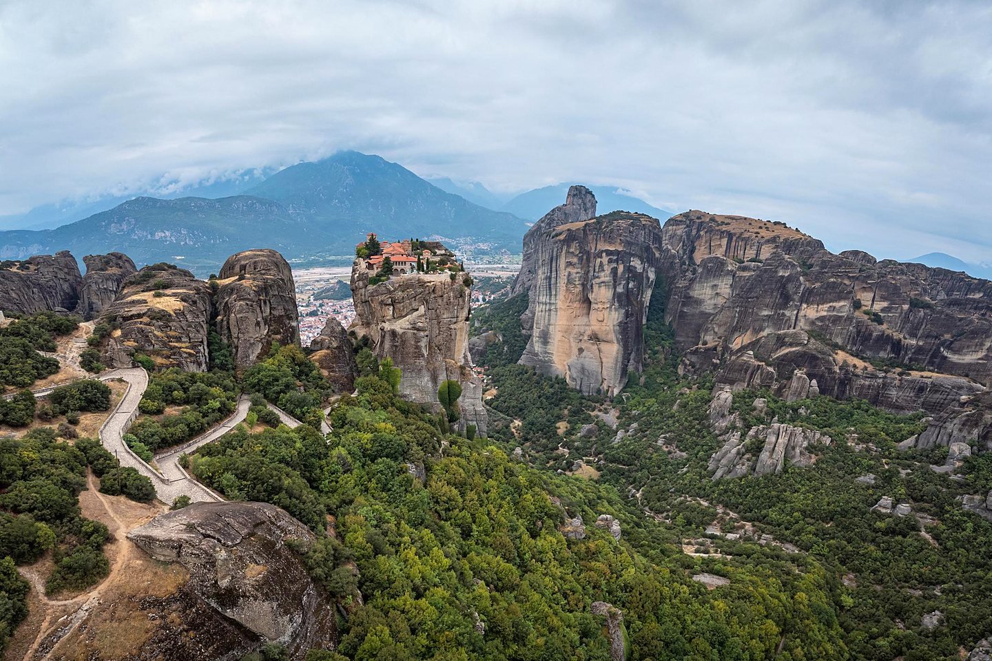 Vista aérea do Mosteiro da Santíssima Trindade no alto do rochedo em Meteora, com Kalambaka e as montanhas ao fundo