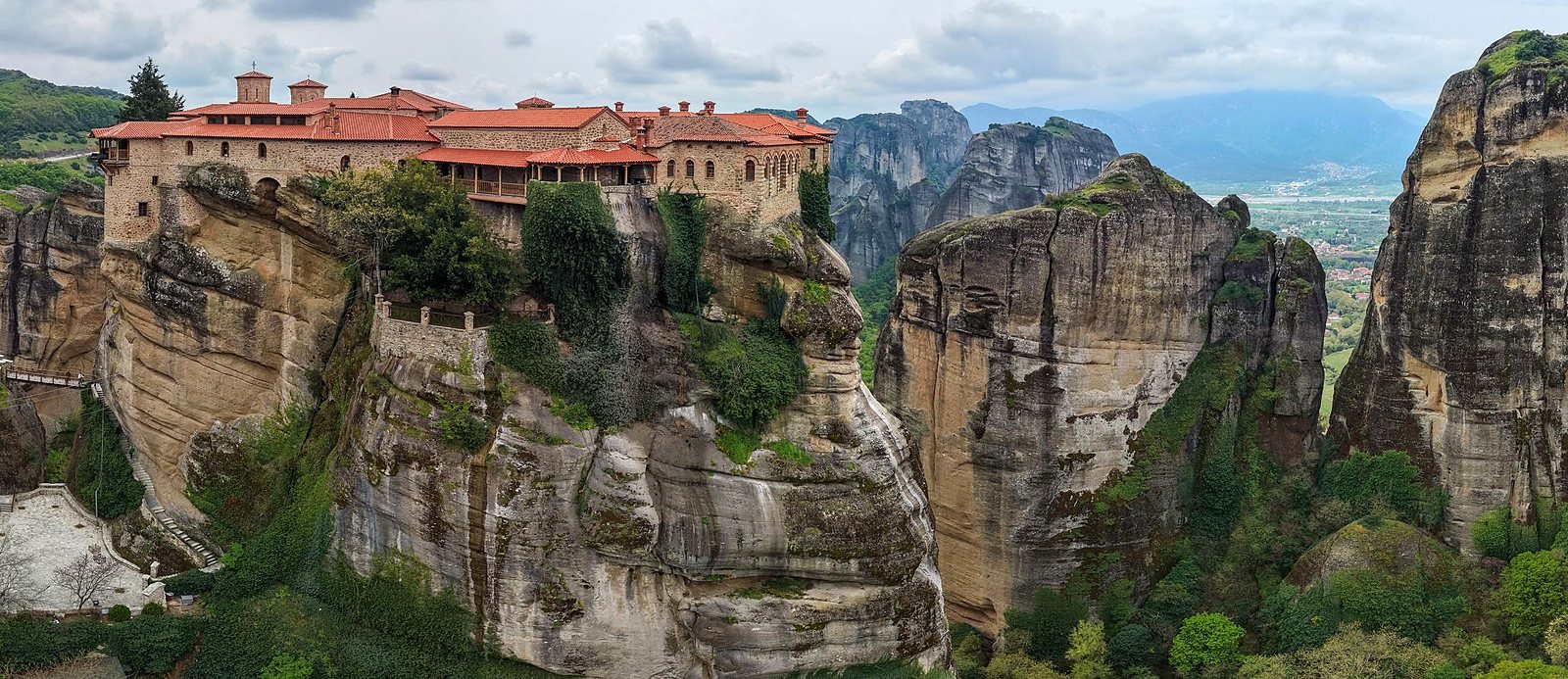 Mosteiro de Varlaam no alto do rochedo em Meteora, com os pilares de rocha e o vale de Kalambaka ao fundo