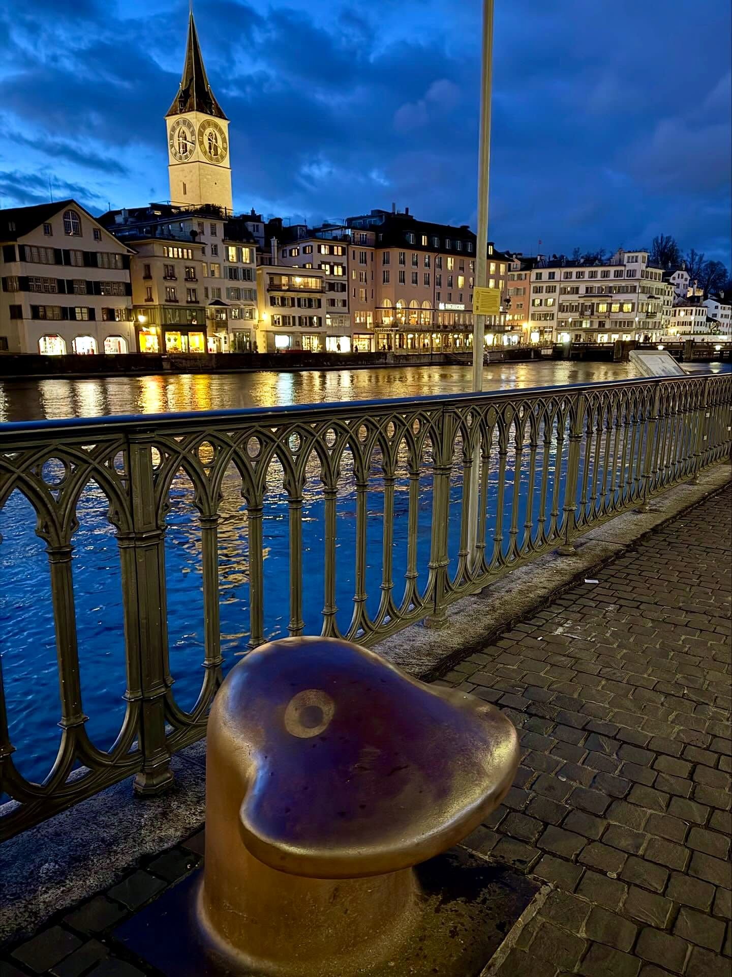 Igreja de São Pedro iluminada à noite às margens do rio Limmat em Zurique