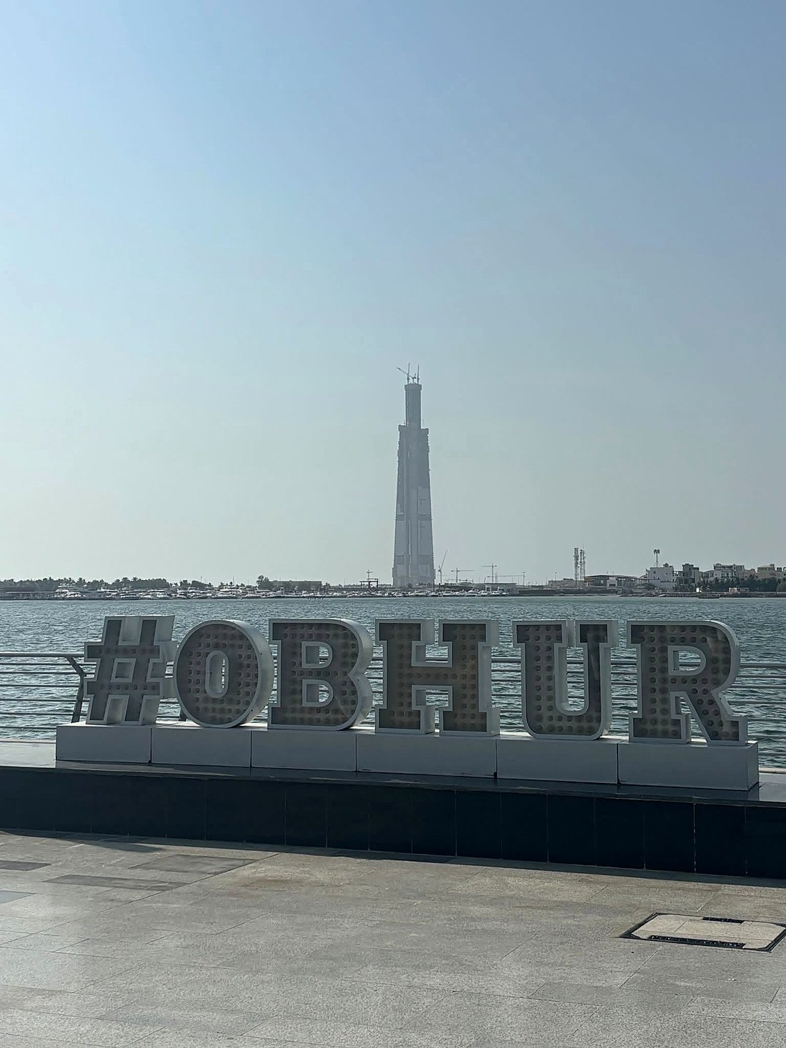Letreiro #OBHUR na orla de Obhur com a Jeddah Tower ao fundo