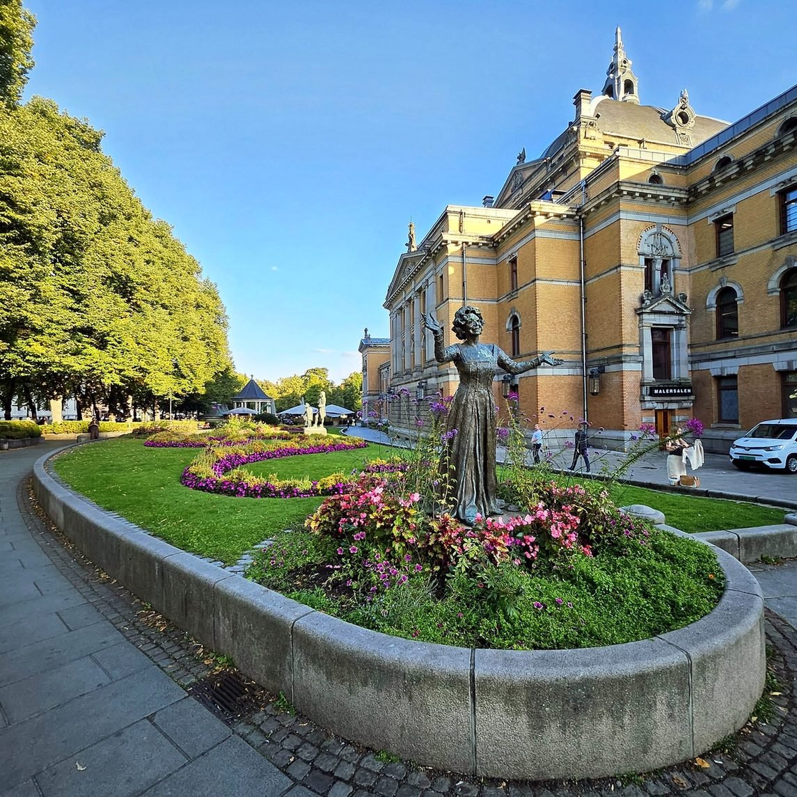 Teatro Nacional de Oslo com jardim florido e estátua