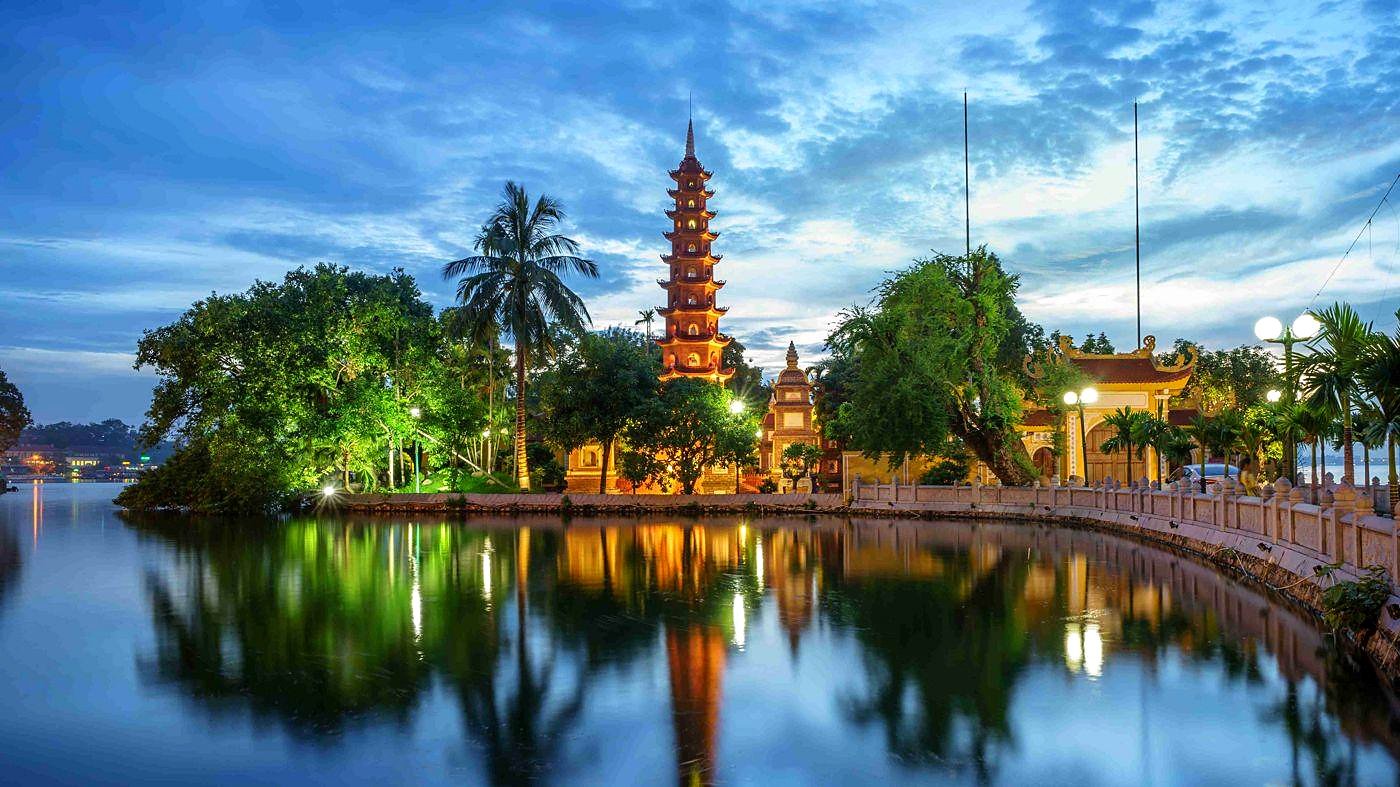 Pagode Tran Quoc iluminado &agrave; noite e refletido no Lago Oeste de Han&oacute;i