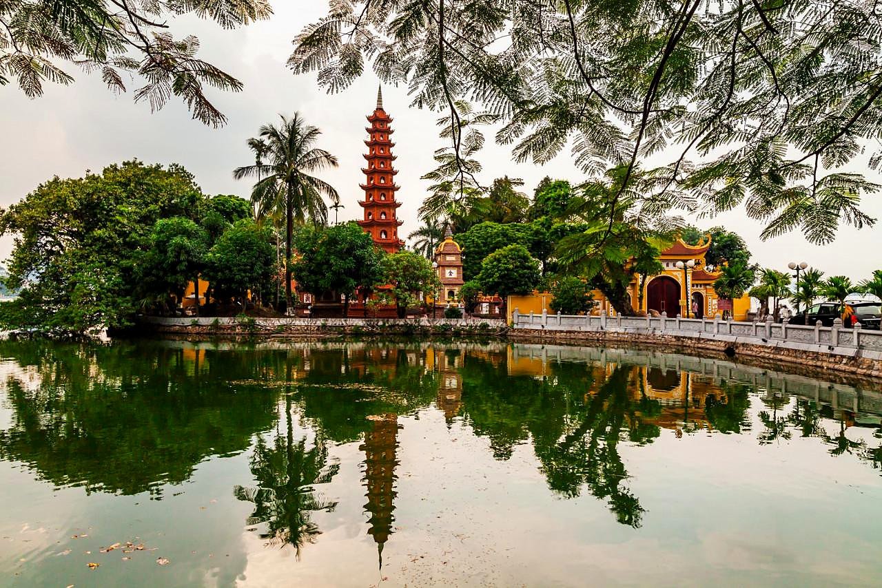 Pagode Tran Quoc visto entre galhos de &aacute;rvores, &agrave; beira do Lago Oeste de Han&oacute;i