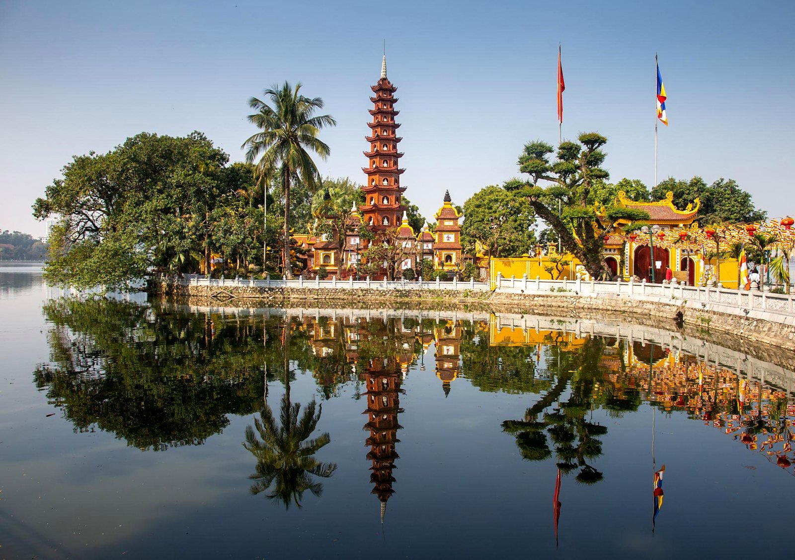 Pagode Tran Quoc e sua torre vermelha refletidos no Lago Oeste, em Han&oacute;i