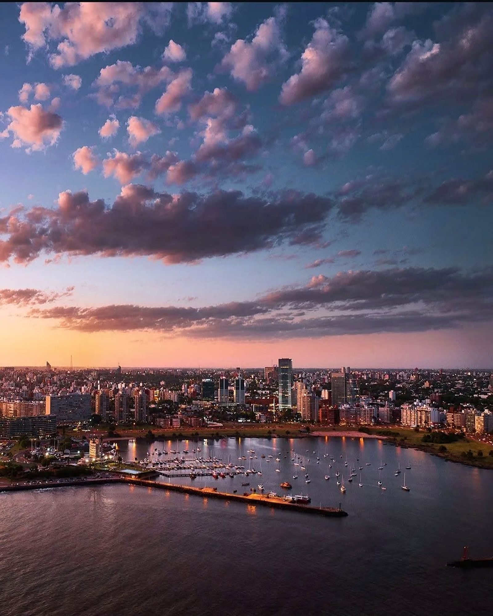 Vista aérea de Montevidéu ao pôr do sol, com o Puertito del Buceo e os prédios da Rambla