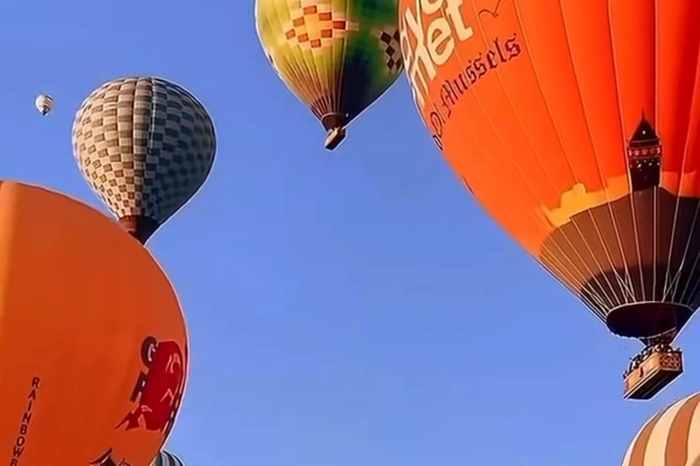Balões coloridos subindo no céu azul da Capadócia