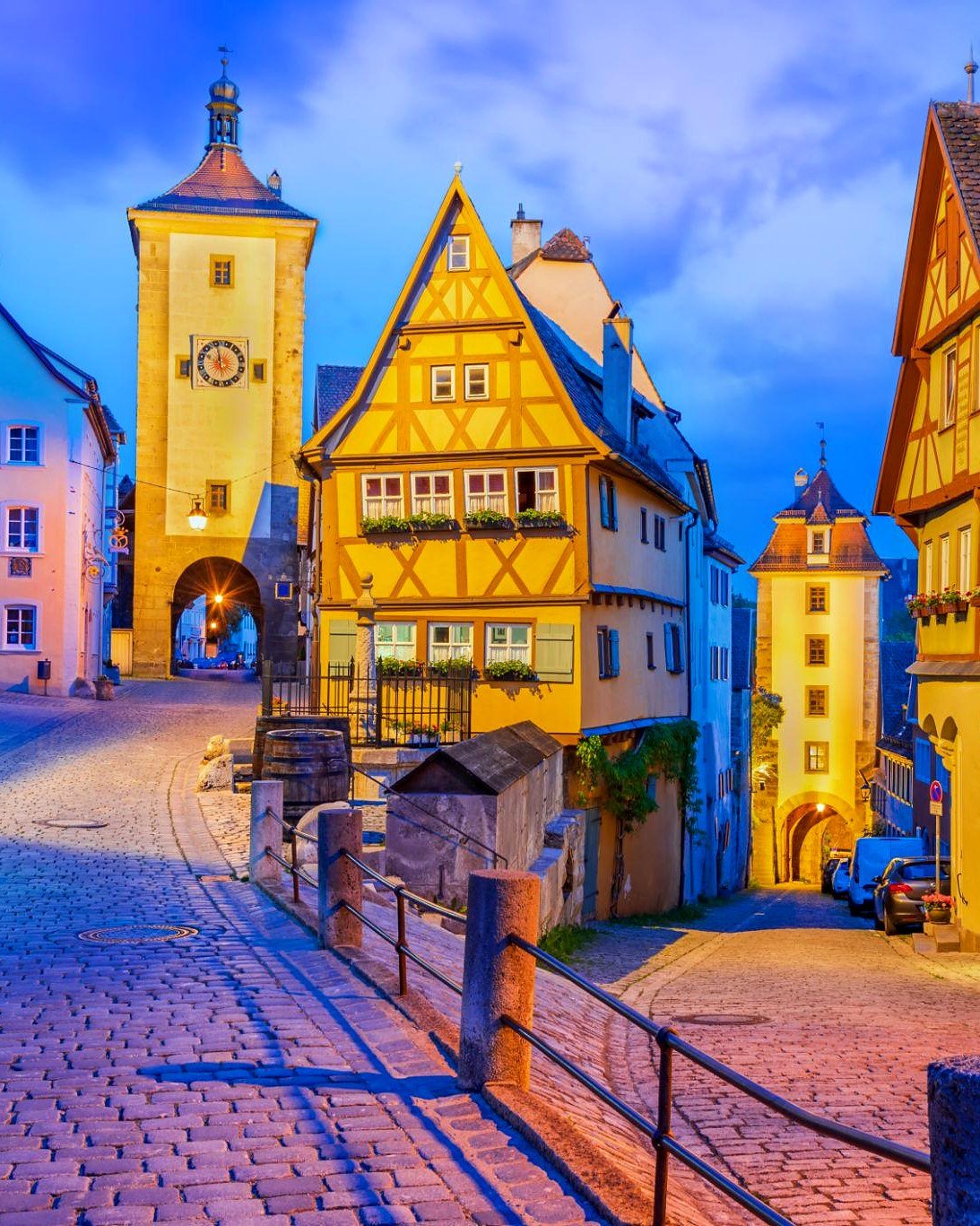 Plönlein ao anoitecer, com a casa de enxaimel amarela entre a torre Siebersturm e a Kobolzeller Tor, em Rothenburg ob der Tauber