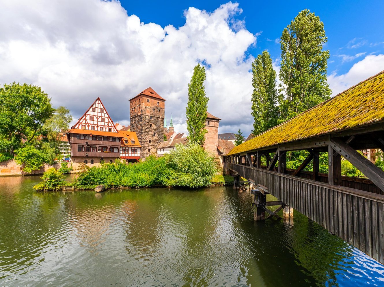 Ponte coberta Henkersteg sobre o rio Pegnitz, com a Torre da Água e a casa de enxaimel Weinstadel em Nuremberg