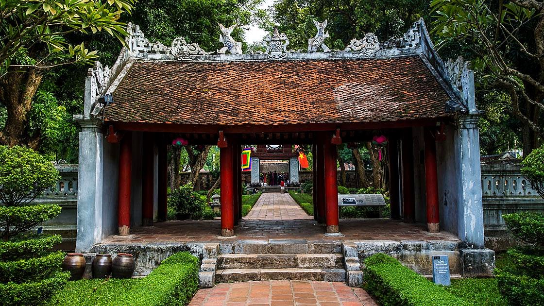 Port&atilde;o interno com telhado tradicional e colunas vermelhas no Templo da Literatura, em Han&oacute;i