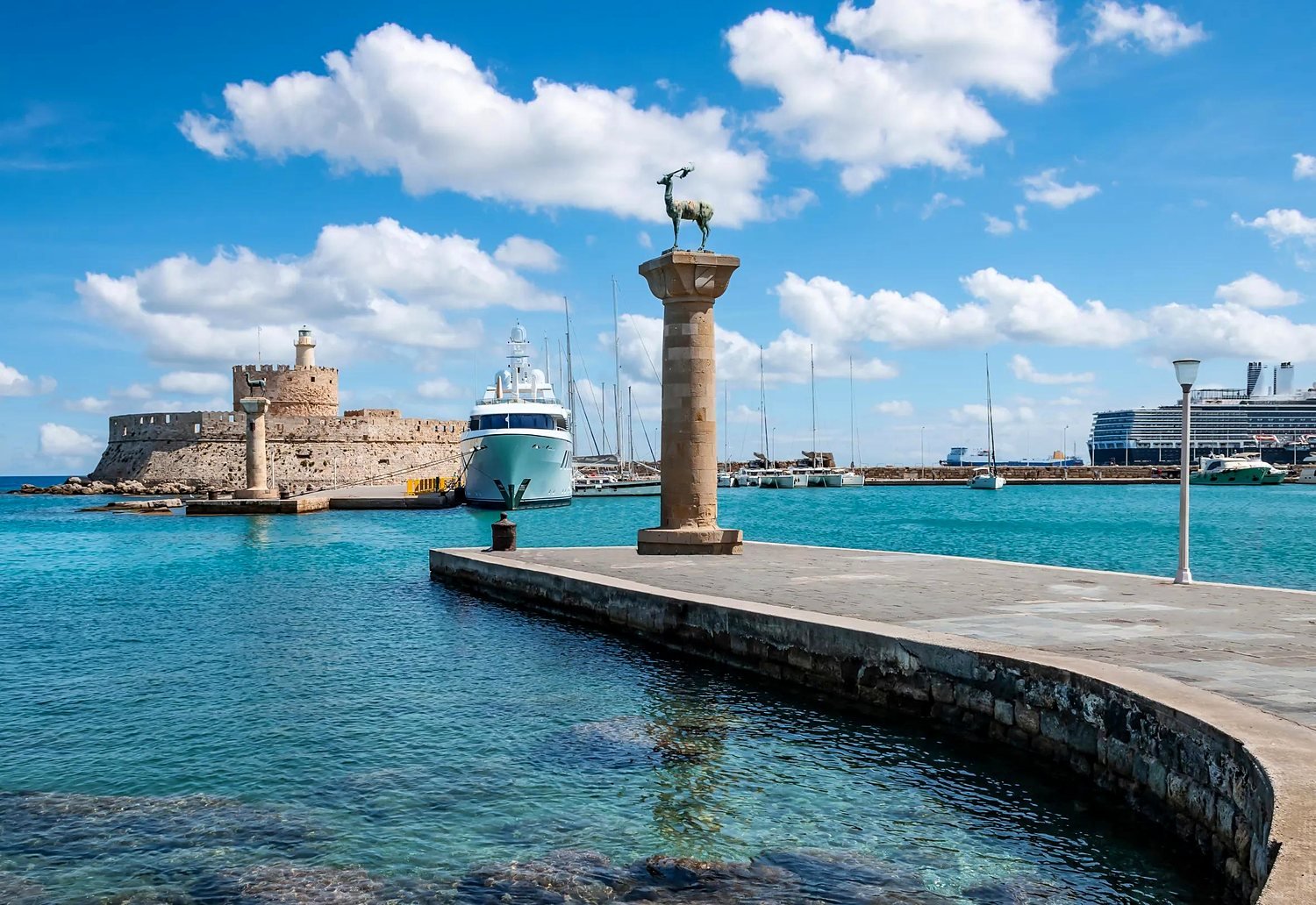 Coluna com a estátua do cervo na entrada do porto de Mandraki e o Forte de São Nicolau, em Rodes