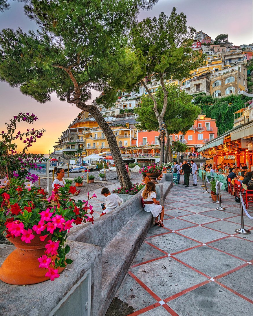 Orla de Positano ao pôr do sol com restaurantes e flores