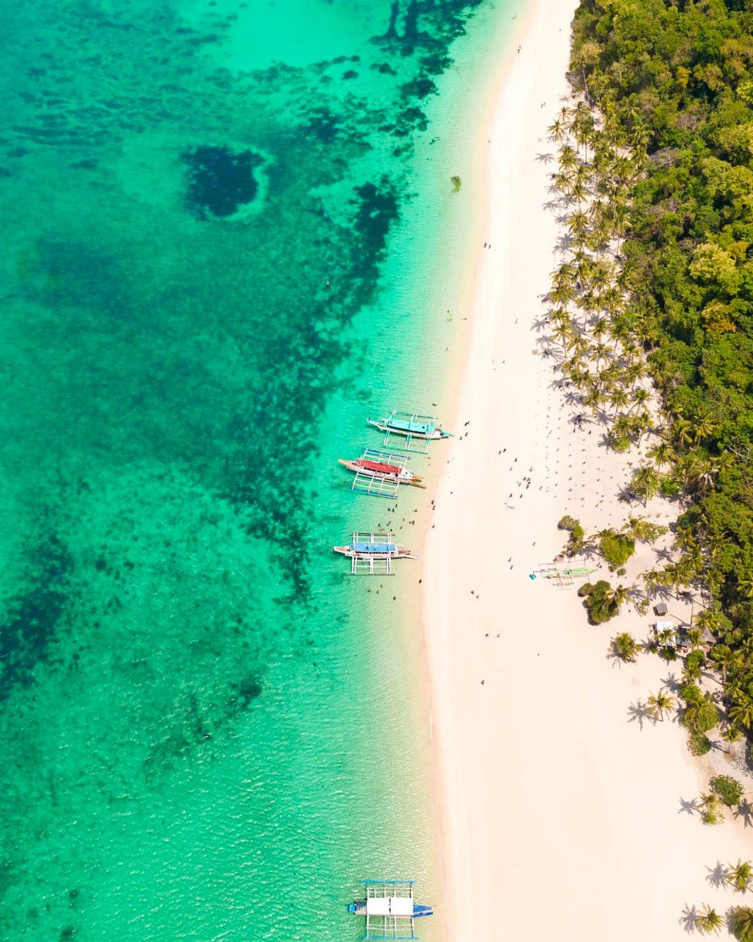 Vista de cima de praia no norte de Boracay, com barcos bangka, corais e coqueiros