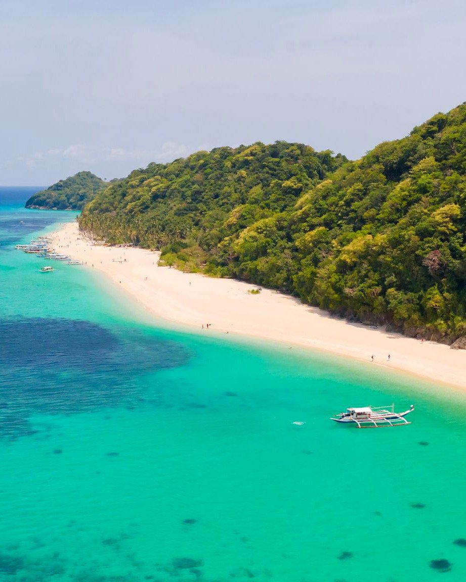 Vista a&eacute;rea da Puka Shell Beach com barco bangka no mar turquesa de Boracay