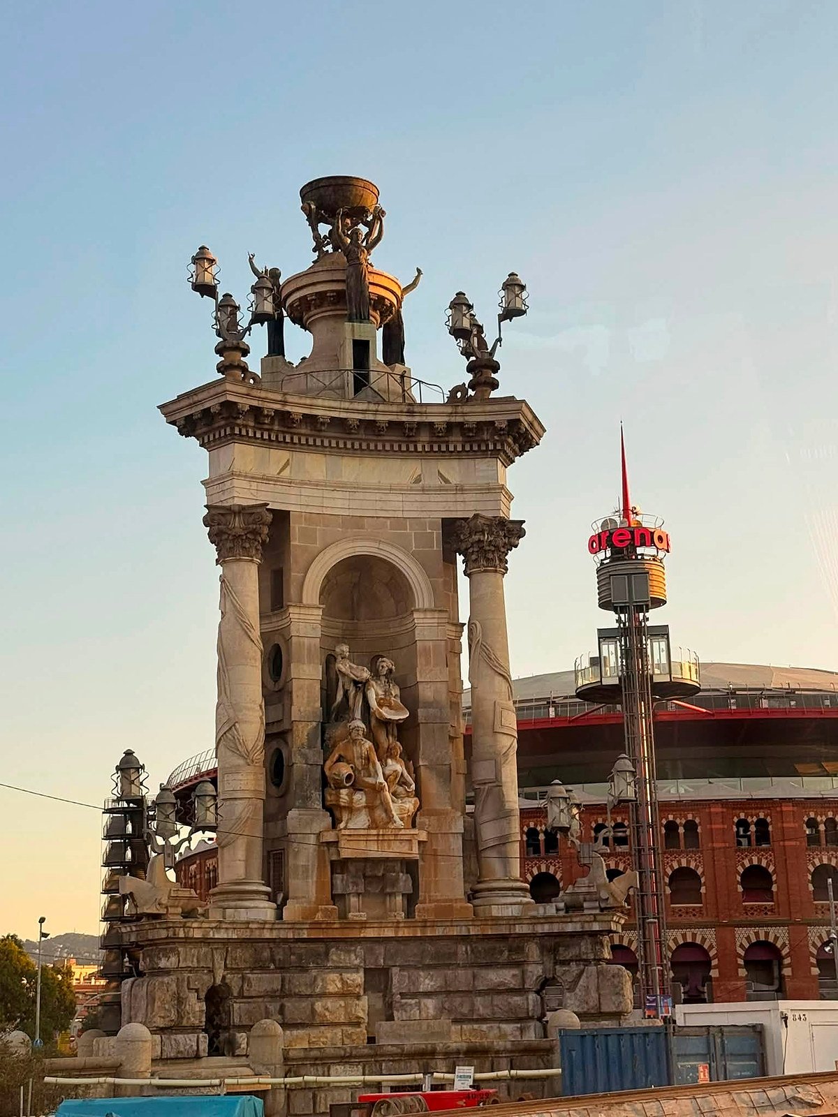 Fonte monumental da Plaça d'Espanya em Barcelona ao entardecer, com o antigo Arenas ao fundo
