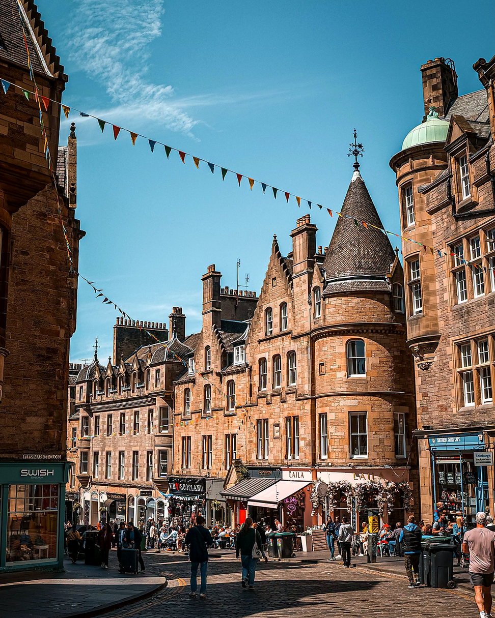 Cockburn Street em Edimburgo com bandeirinhas coloridas e prédios de pedra