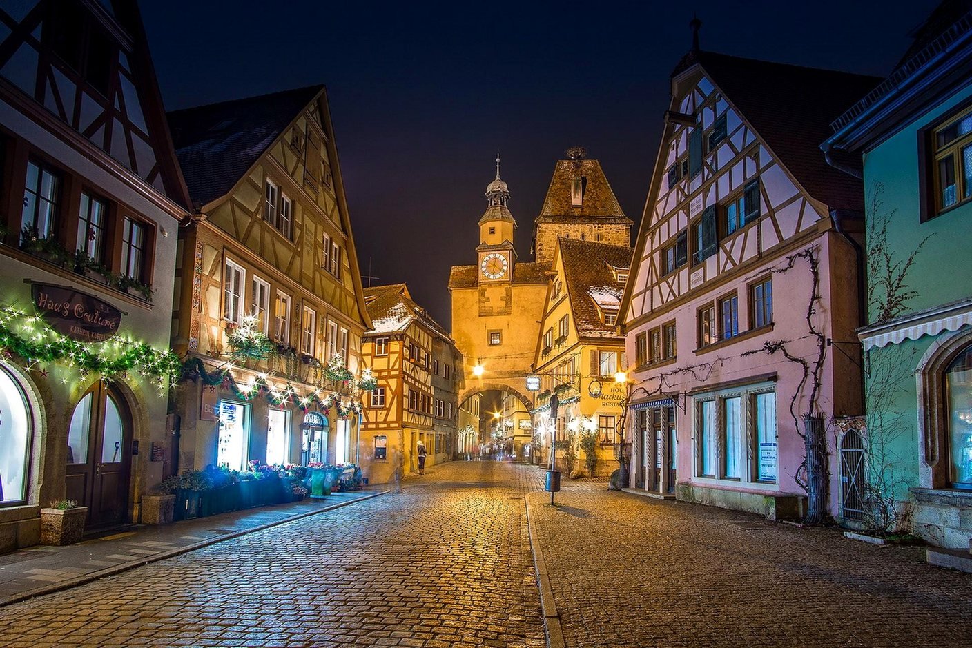 Rua de pedra com casas de enxaimel iluminadas e a torre Markusturm com o arco R&ouml;derbogen &agrave; noite, em Rothenburg ob der Tauber