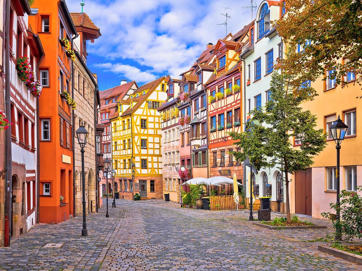 Fachadas coloridas, flores nas janelas e postes antigos na rua Weißgerbergasse, em Nuremberg