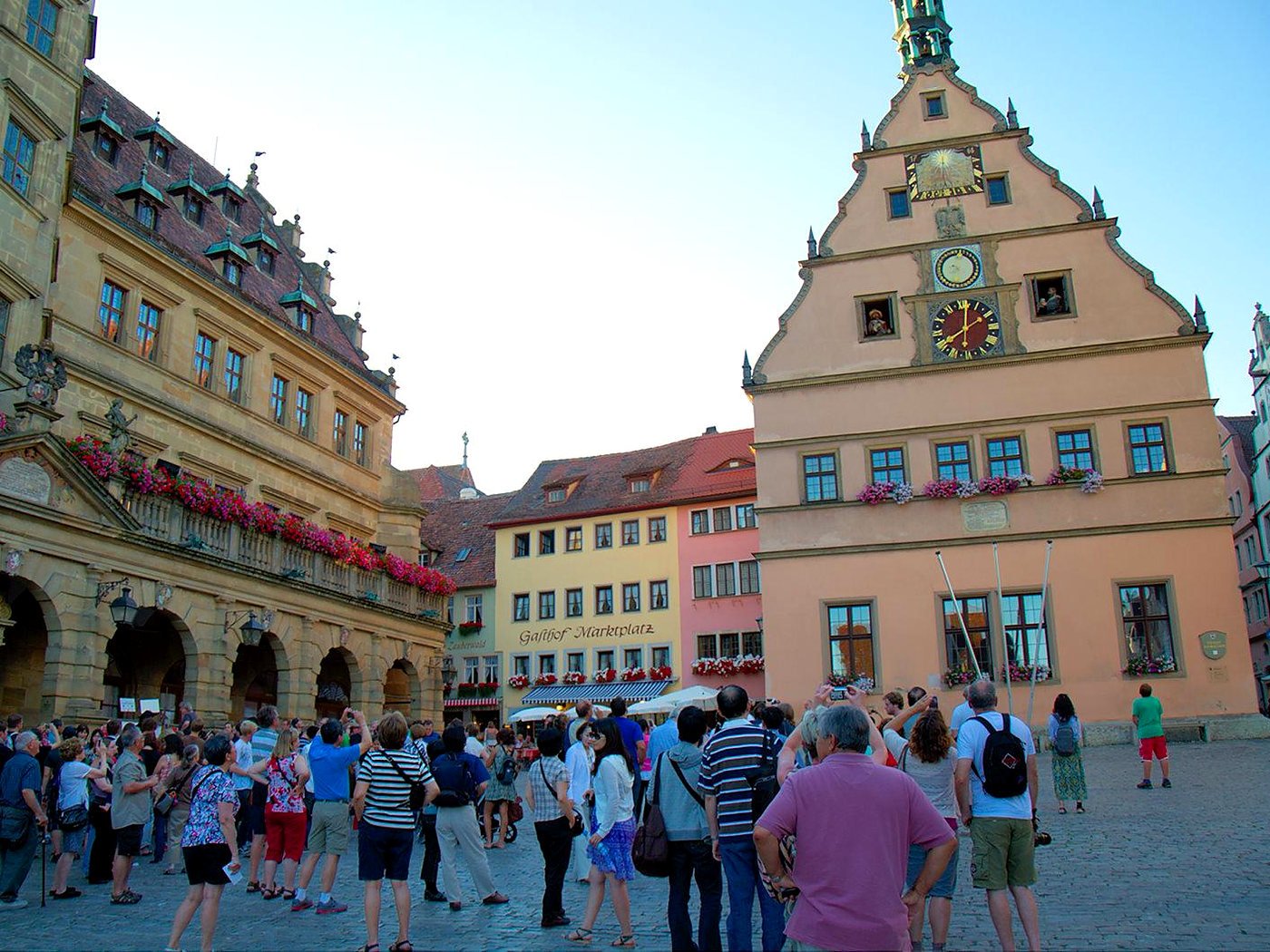Turistas na Marktplatz de Rothenburg assistindo às figuras do Meistertrunk nas janelas do relógio da Ratstrinkstube