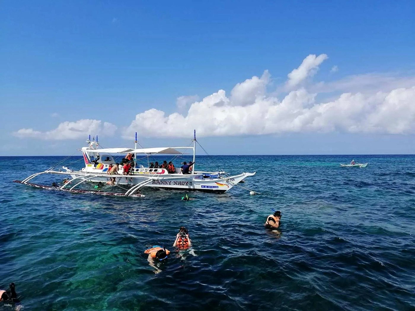 Turistas fazendo snorkel com colete salva-vidas ao lado de barco bangka em Boracay