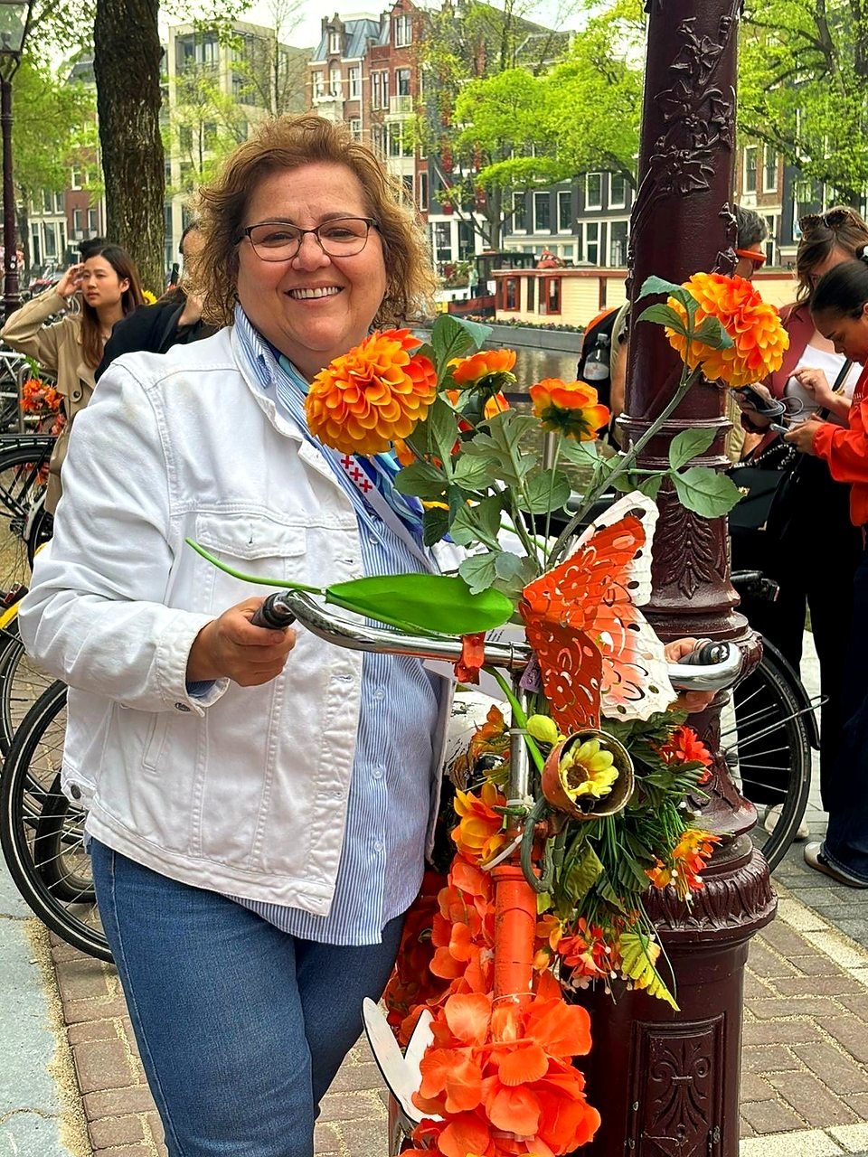 Tatiana Gervásio, guia brasileira credenciada na Holanda, ao lado de uma bicicleta decorada com flores laranja