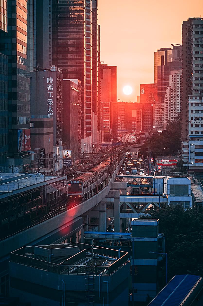 Trem do metrô MTR entre arranha-céus de Hong Kong ao pôr do sol