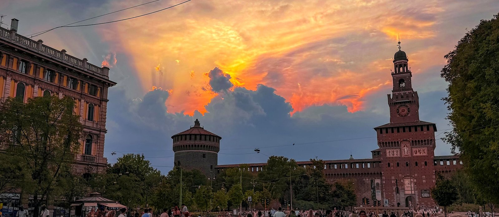 Castello Sforzesco ao pôr do sol em Milão, Itália, com a Torre del Filarete e a praça cheia de turistas