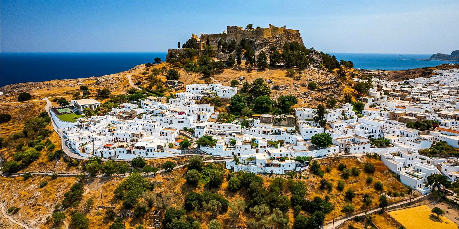 Vila de casas brancas de Lindos com a acrópole no alto do morro, em Rodes