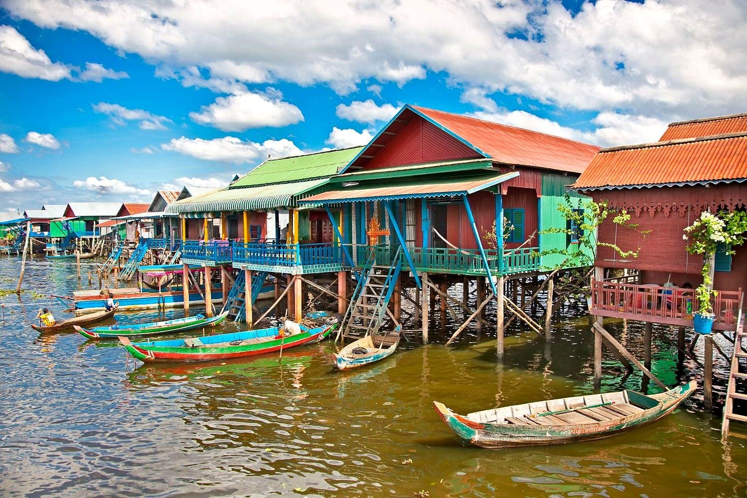 Casas coloridas sobre palafitas e barcos na vila flutuante do lago Tonlé Sap