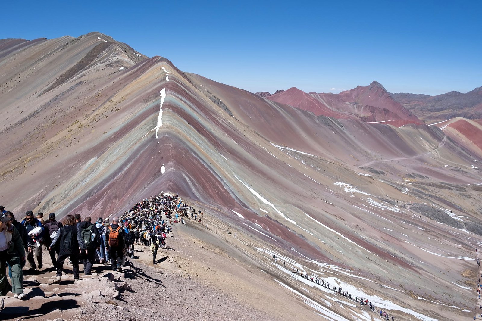 Montanha Colorida de Vinicunca com faixas de cores e visitantes na trilha