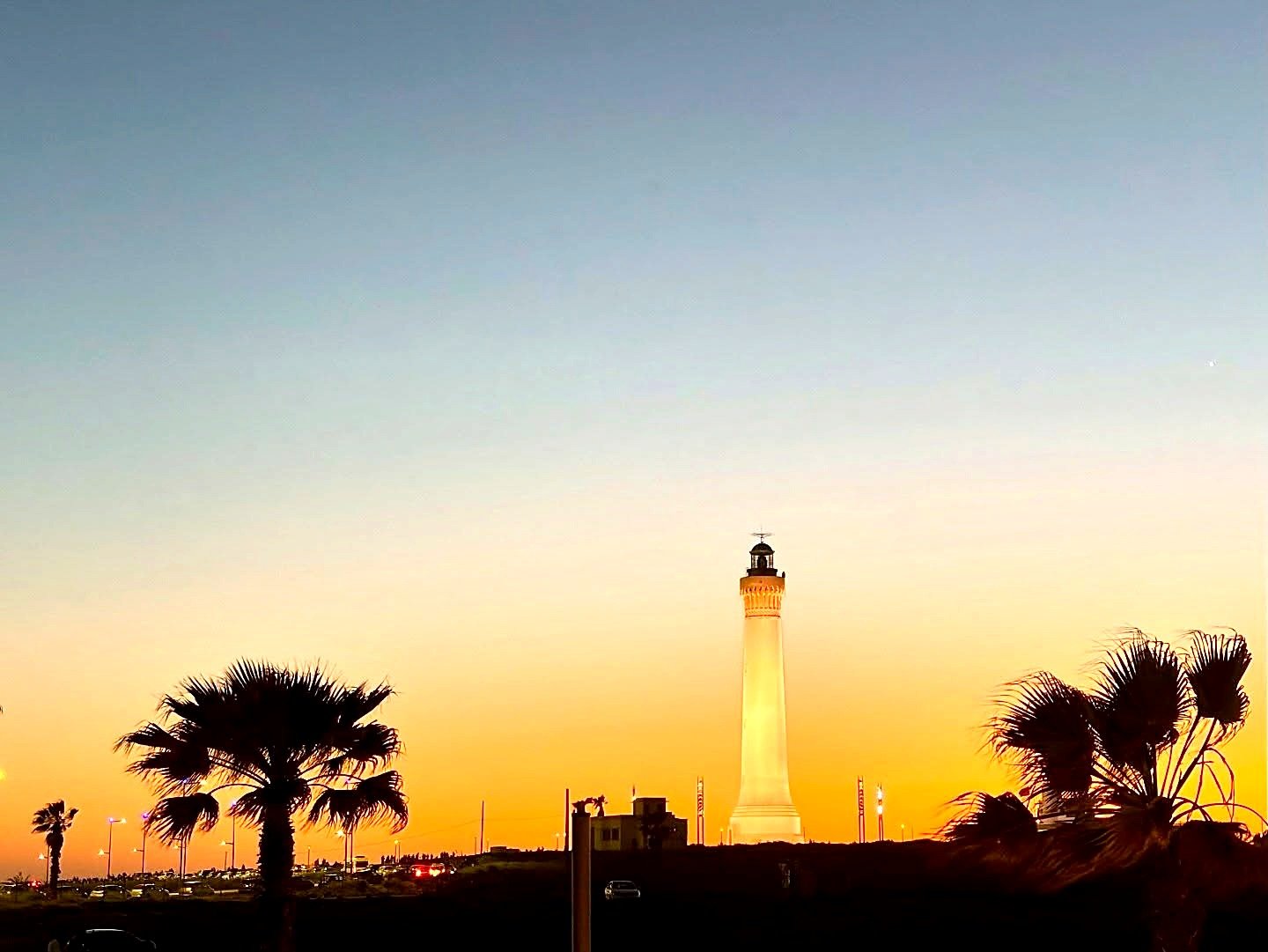 Farol de El Hank iluminado ao pôr do sol em Casablanca, entre palmeiras