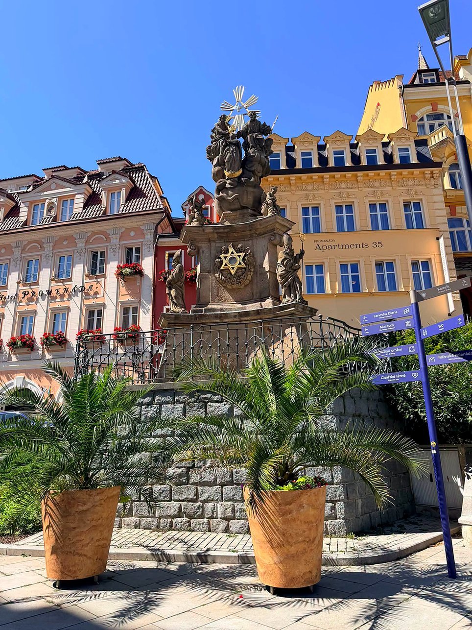 Coluna barroca da Santíssima Trindade diante de hotéis coloridos em Karlovy Vary