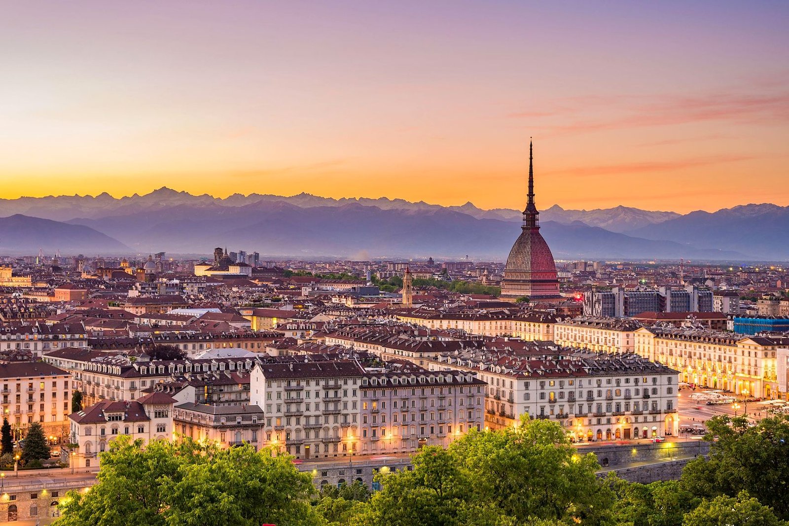 Vista de Turim ao p&ocirc;r do sol com a Mole Antonelliana iluminada e os Alpes ao fundo